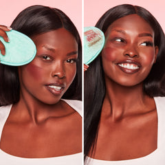 Two women using a green face scrubber on their faces against a pink background