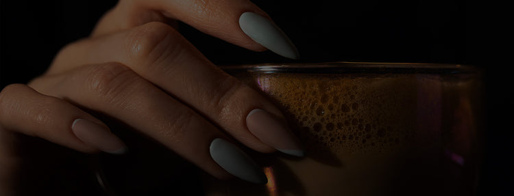 Close-up of a hand with press on nails  holding a an iced coffee. 