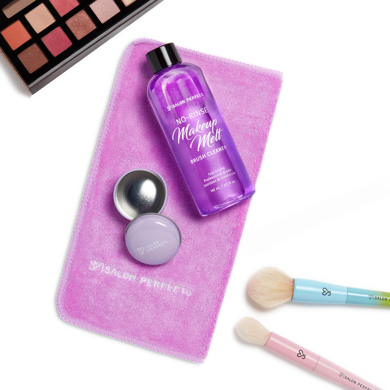 Salon Perfect No-Rinse Makeup Melt brush cleaner with a pink microfiber towel, makeup brushes, and an eyeshadow palette.